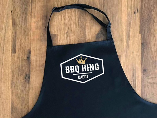 black apron printed with the words BBQ KING and personalised with a name. There is a crown motif above the text