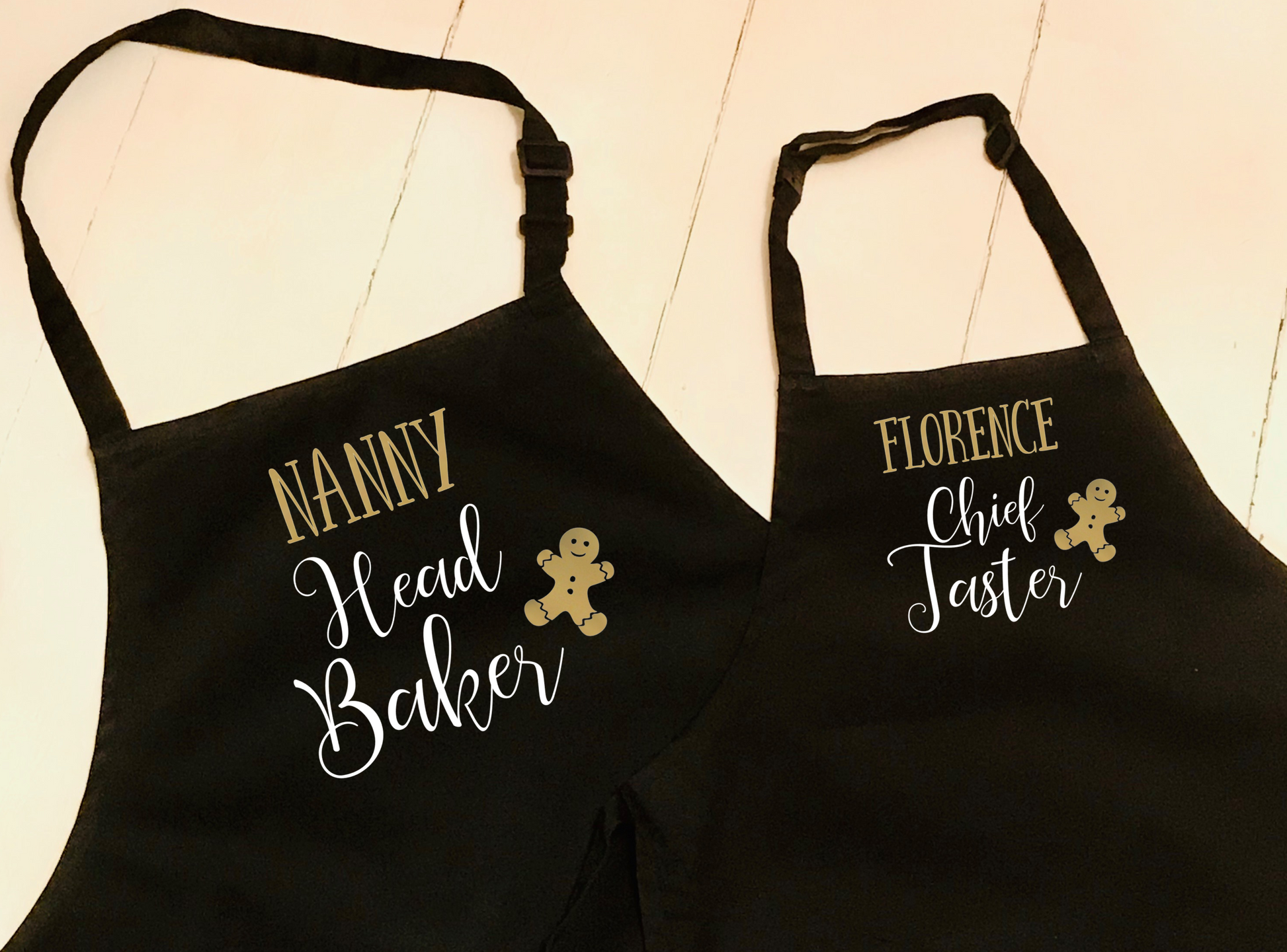 set of two black aprons, one printed with Head Baker, and the other Chief Taster. Can be personalised with names. A Gingerbread man also features in the design