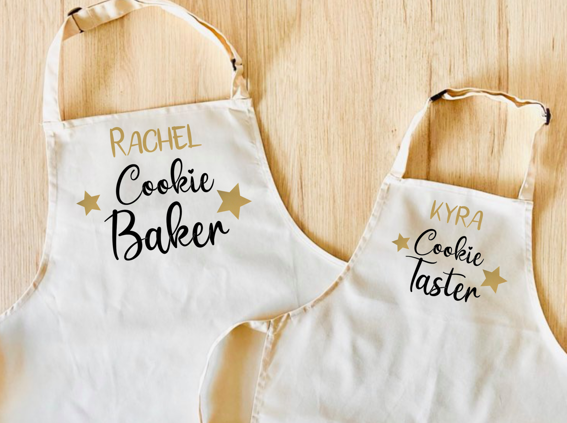set of 2 natural coloured aprons. One says Cookie Baker, the other says Cookie Taster. Can be personalised with names