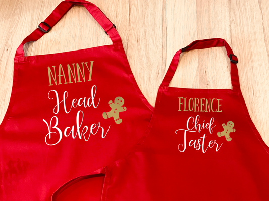 set of two red aprons, with a gingerbread man design. One says Head Baker, the other days Chief Taster. Can be personalised with names